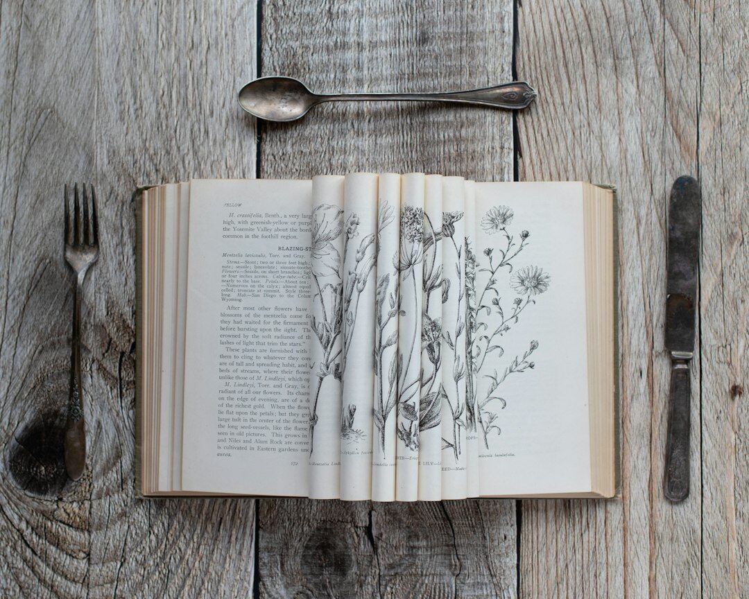 Open antique book with a magnifying glass resting on top on a wooden table