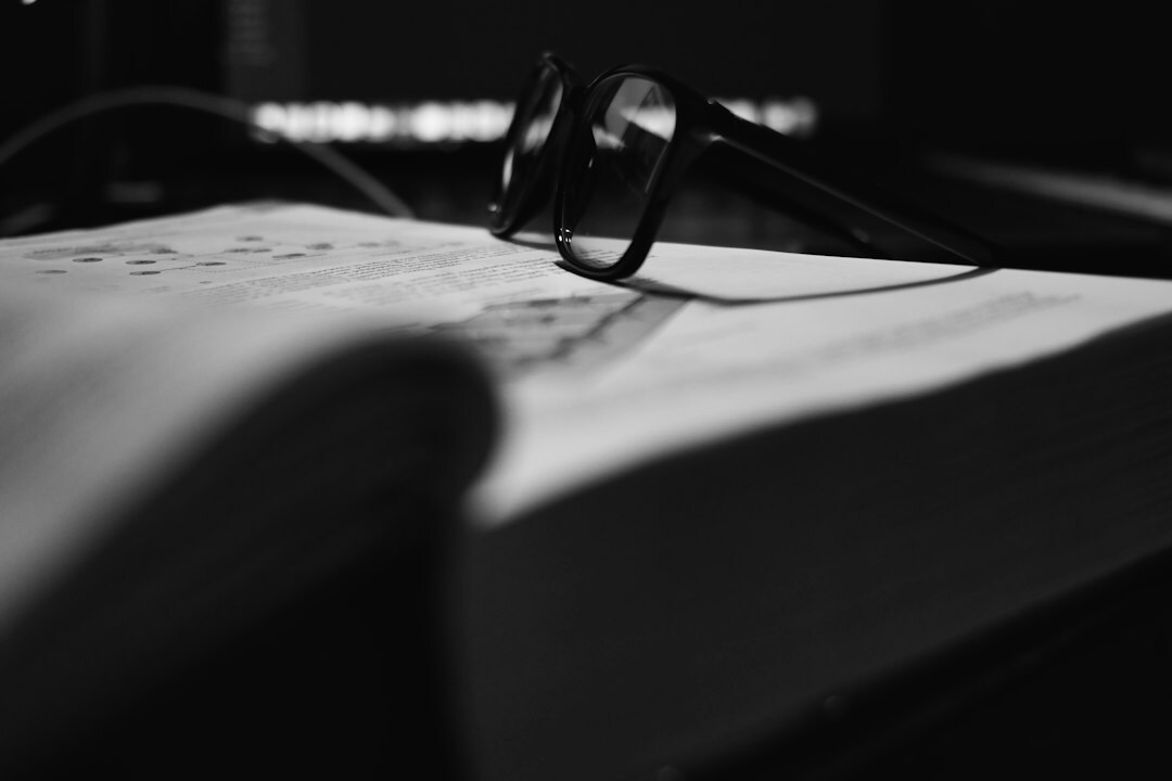 Hand holding a magnifying glass over old documents and photographs on a desk